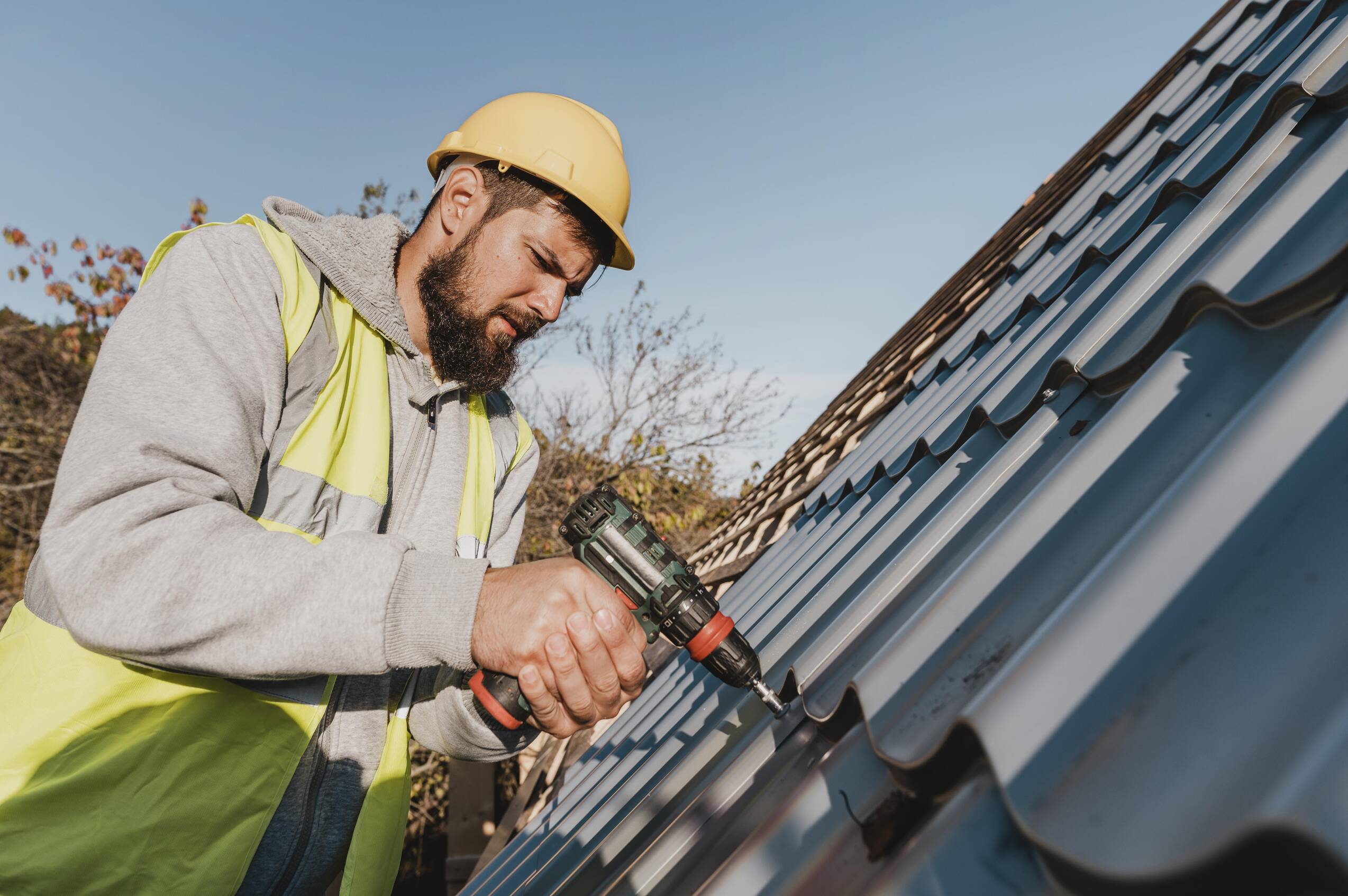 Sideways man working roof with drill